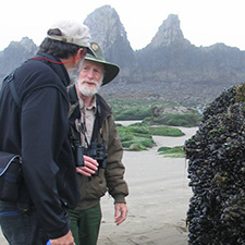 A roving interpretive ranger shares interesting details about mussel beds with a beach visitor.